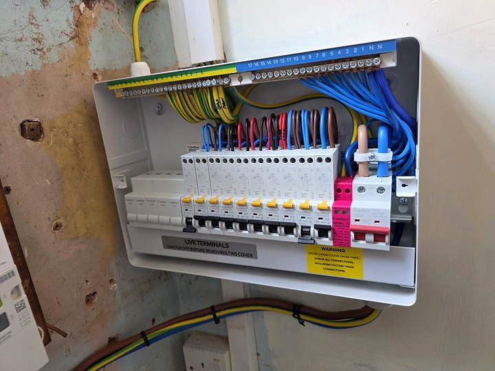 New consumer unit with the cover off, showing neatly dressed wiring, RCBOs and a surge protection device