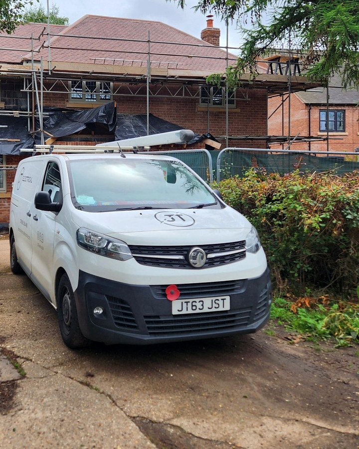 White JT Electrical van parked on site in front of a house under scaffolding