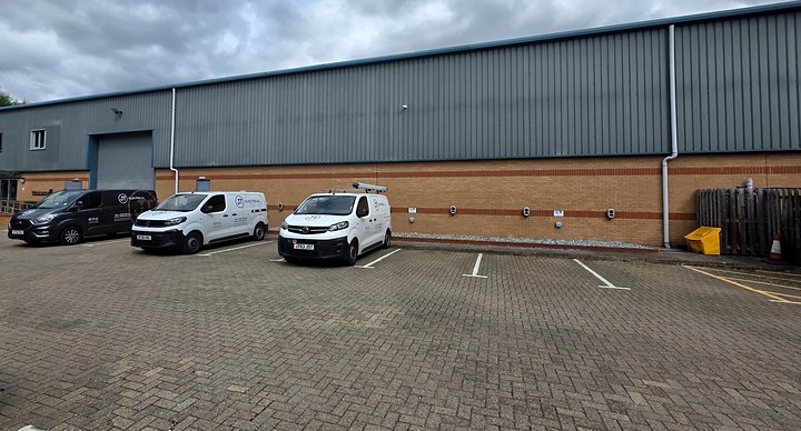 JT Electrical vans parked outside an industrial unit with newly fitted EV chargers along its wall